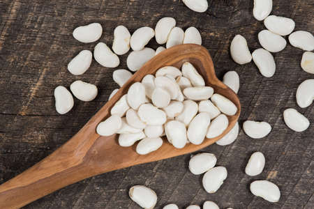 Lima beans in a wooden spoon on rustic wooden board