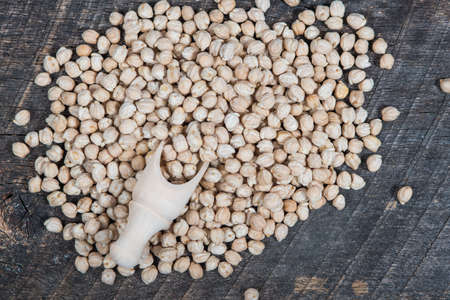 Chick peas scattered on wooden board with a wooden scoopの写真素材