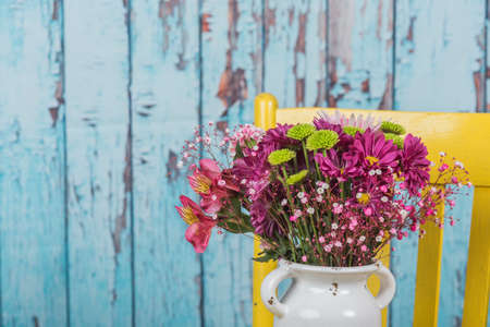 Bouquet of flowers sitting in an old yellow chair.