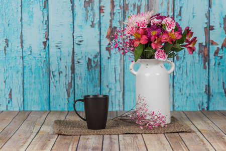 Vintage white vase with flowers and a mug with a peeled paint backgroundの写真素材