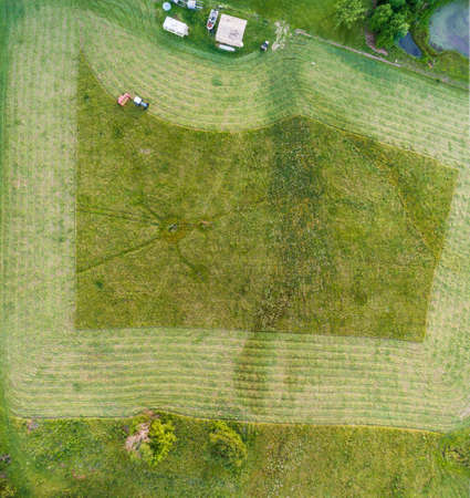 Tractor pulling a hay cutter showing the pattern in a small hay fieldの写真素材