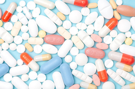 Top view flat lay of various pills on blue background. Ideal for healthcare, pharmacy, medical,...