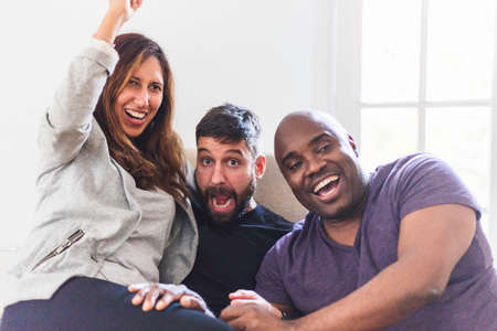 three interracial people celebrating and enjoying a great afternoon together, we ave a black man, a spanish man and finally a latin womenの写真素材