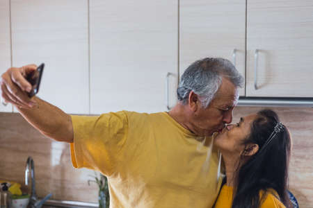 Old couple taking a selfie while kissing.の写真素材