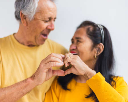 Happy old couple doing a heart with their handsの写真素材