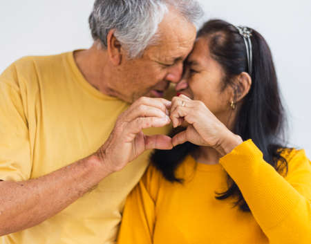 Unrecognizable old couple doing a heart with their hands while kissingの写真素材