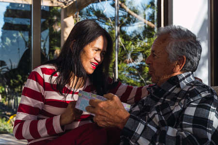 Old interracial couple at Valentines day gibing presentsの写真素材