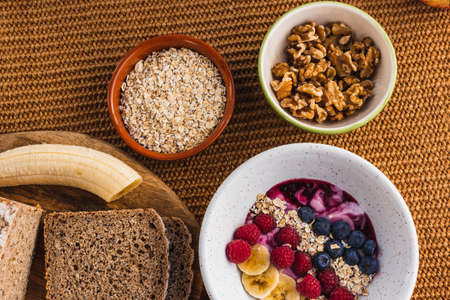 Healthy breakfast with brown bread, nuts and a fruit bowlの写真素材