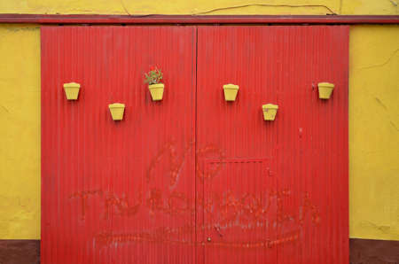 red garage door and yellow flowerpotsの写真素材