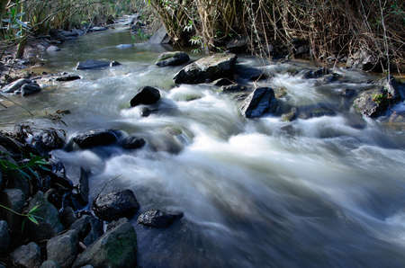 A mountain river flowing through stones  Water is blurred because of streaming, movement and long exposure の写真素材