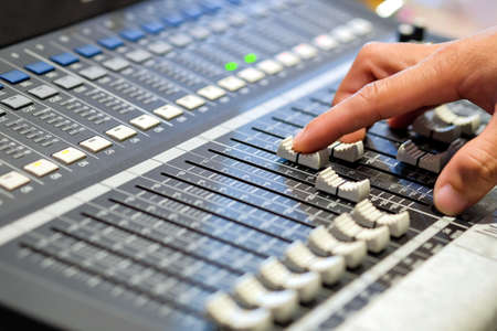 Sound engineer's fingers are pressing the button audio controller in recording room.の写真素材