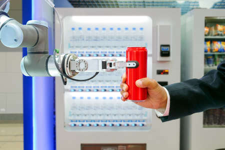 Close-up industrial robotic gripping red soda can for sending to businessman via smart automatic...