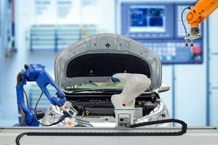 Industrial robotic teamwork working with automobile on blurred smart factory blue tone color background, robot work instead of human, industry 4.0 and AI conceptの写真素材