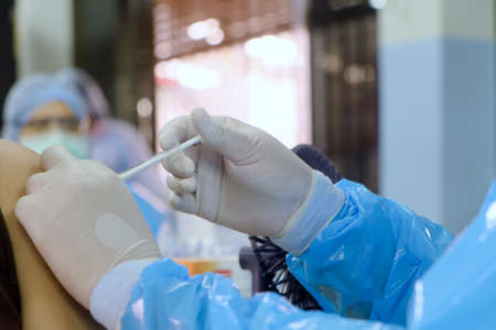 Close-up and selective focus of doctor hand who is vaccinating on upper arm of people for build...
