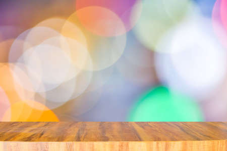 Empty long modern wooden counter on top for placing items and anything on blurred multicolored light...