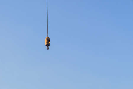 Iron hook with iron sling cable of giant crane for lift object on construction site work with blue sky background and copy spaceの写真素材