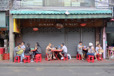 Bangkok-Thailand JUL 30 2019: Unidentified people and traveler sit down on red chairs to eat street food and beverage on footpath at Chinatown (Yaowarat) on Bangkok, Thailandのeditorial素材
