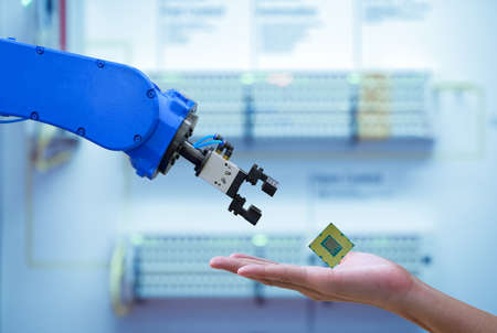 Close-up CPU chipset processor on hand human for sending to automation robot for upgrade efficiency to work on smart factory, blue tone color background, industry industry 4.0の写真素材