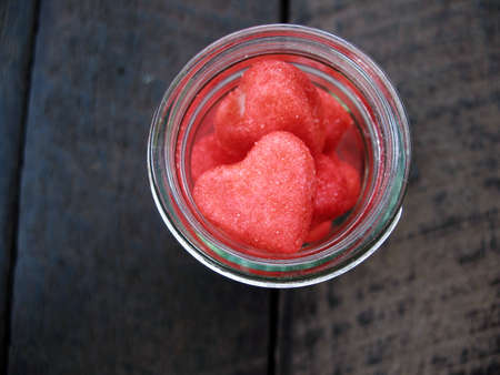 open glass bottle with many little heart on old wood backgroundの写真素材