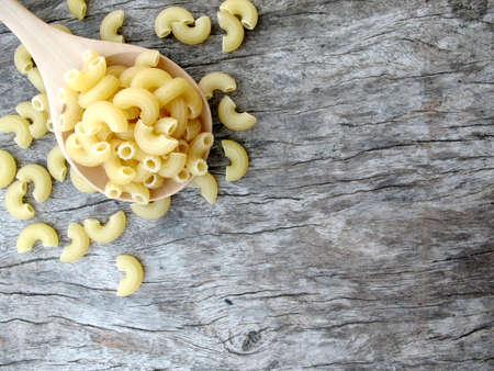 italian macaroni on wooden spoon and old wood textureの写真素材