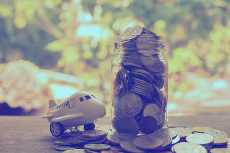 stack money coin in glass with airplane toy concept saving money for travel and journey.の写真素材