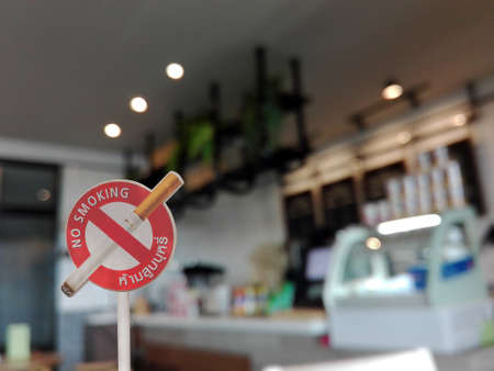 No smoking sign with English and thai wording on blur coffee shopの写真素材