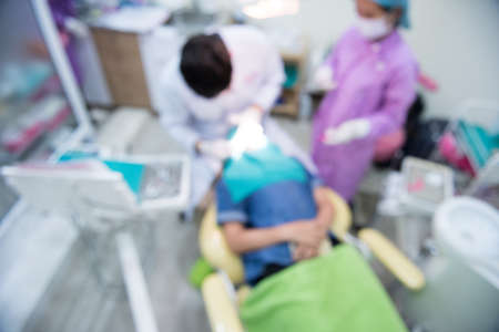 Blurred abstract background of dentistry care unit room interior in dental hospital clinic with dentist and assistants working on patient's tooth care using equipment, instrument on dental chairの写真素材