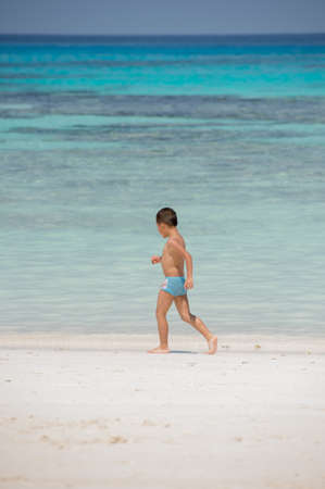 The boy running on the beach background blue seaの写真素材