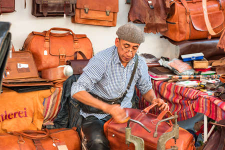 Leather manufacturing: craftsman or leather-dresser surrounded by leather goods at work polishing very Quickly a new leather bag - September 24 2016, falling market, Heidelberg, Germanyのeditorial素材