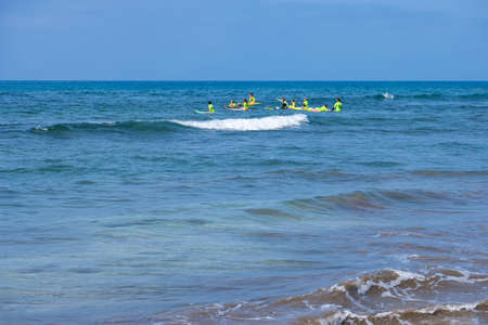 Surfing lesson in Maspalomas: group of surfboard learners with instructors in the sea by practicing. Maspalomas, Gran Canaria, Canary Islands, Spain - July 18 2017のeditorial素材