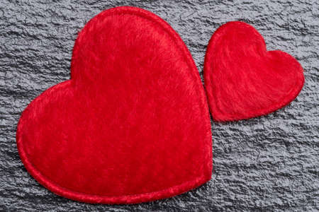 Love concept - two red fluffy hearts over rough black slate backgroundの写真素材