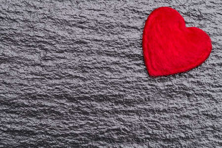 Red fluffy heart over black slate background with copy spaceの写真素材