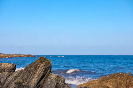 Closeup of rocks with azure ocean and clear blue sky in the backgroundの写真素材