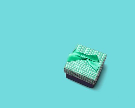 Surprise gift. Box with turquoise ribbon as a gift for the holiday, on a blue background, top view.