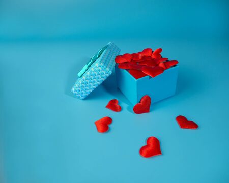 Bright, blue gift box with red hearts on a blue background.の写真素材