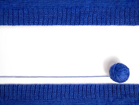 Knitting on needles. Top view of a blue ball of yarn on a white background, among knitted fabrics....