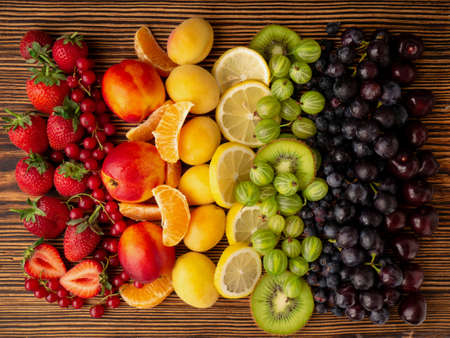 Fresh berries and fruit on a wooden background. Rainbow color. the concept of healthy eating. The view from the topの写真素材