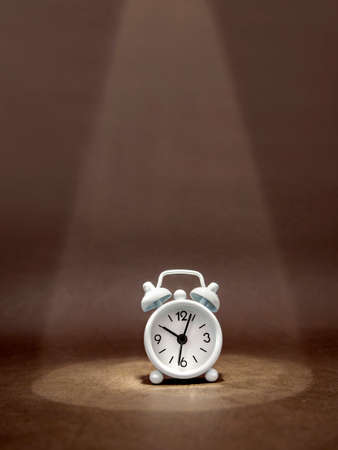 Clock in a beam of light on dark background. Business idea, financial concept and saving money and time. Vertical formatの写真素材