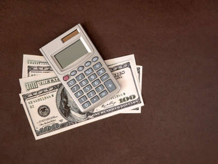 Calculator, coins and banknotes on a dark background. The idea of business, Finance concept and saving money and timeの写真素材