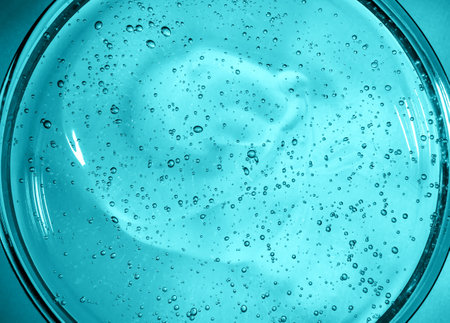 Gel with hyaluronic acid. Blue background with oxygen bubbles. Cosmetic gel in a petri dish.の写真素材