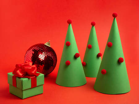 New Years card. Decorative Christmas tree, ball and a gift box on a bright red background. Christmas trinketsの写真素材