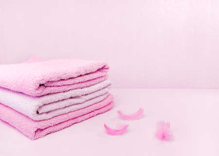 A stack of neatly folded pink bath towels, soft as a feather. Space for textの写真素材