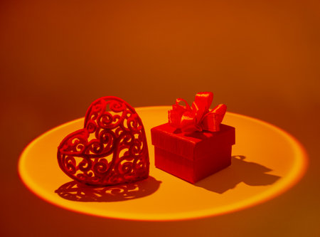 The concept of Valentine's Day. The symbol of love is a heart and a gift box in a circle of bright...