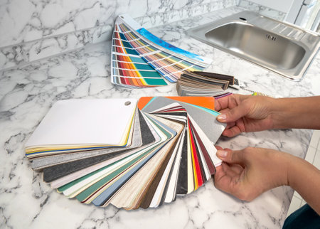 The woman's hands hold a palette of colors and a sample of materials for making kitchen furniture