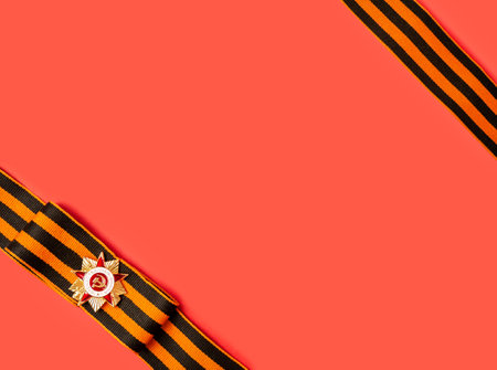 Victory Day 1945. The holiday is May 9th. St. George ribbon and medal on a red background with a place for text. The inscription on the Order of the Patriotic Warの写真素材