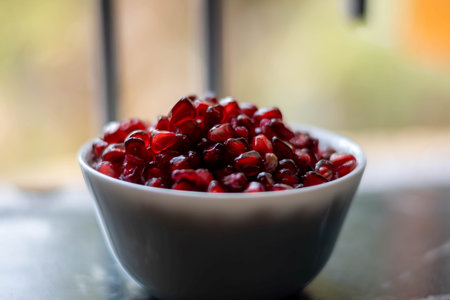 Pomegranate seeds in a bowl on the table. Selective focus.