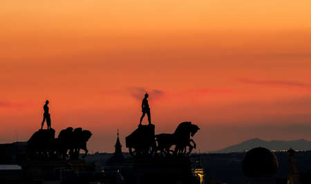 Two equestrian sculptures with chariot on a Madrid rooftop at sunset.の写真素材