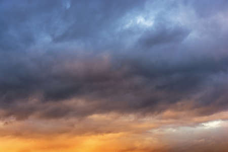 Gray rain clouds in the rays of the sun at sunset. Thunderclouds in dark blue. Sky with clouds at...