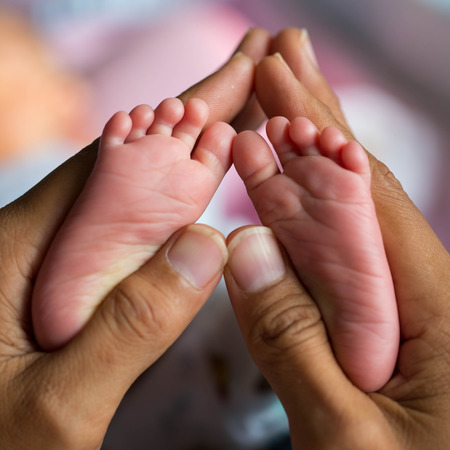 baby feet holding by mother hand like heart shapeの写真素材