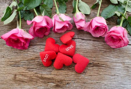 Roses and Red heart pillow on old wooden board, Valentines Day background, wedding day.Postcard / greeting card. Pink roses on textured wooden background. Copy space, top view. Panoramaの写真素材